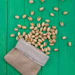 top-view-pistachios-burlap-bag-green-surface